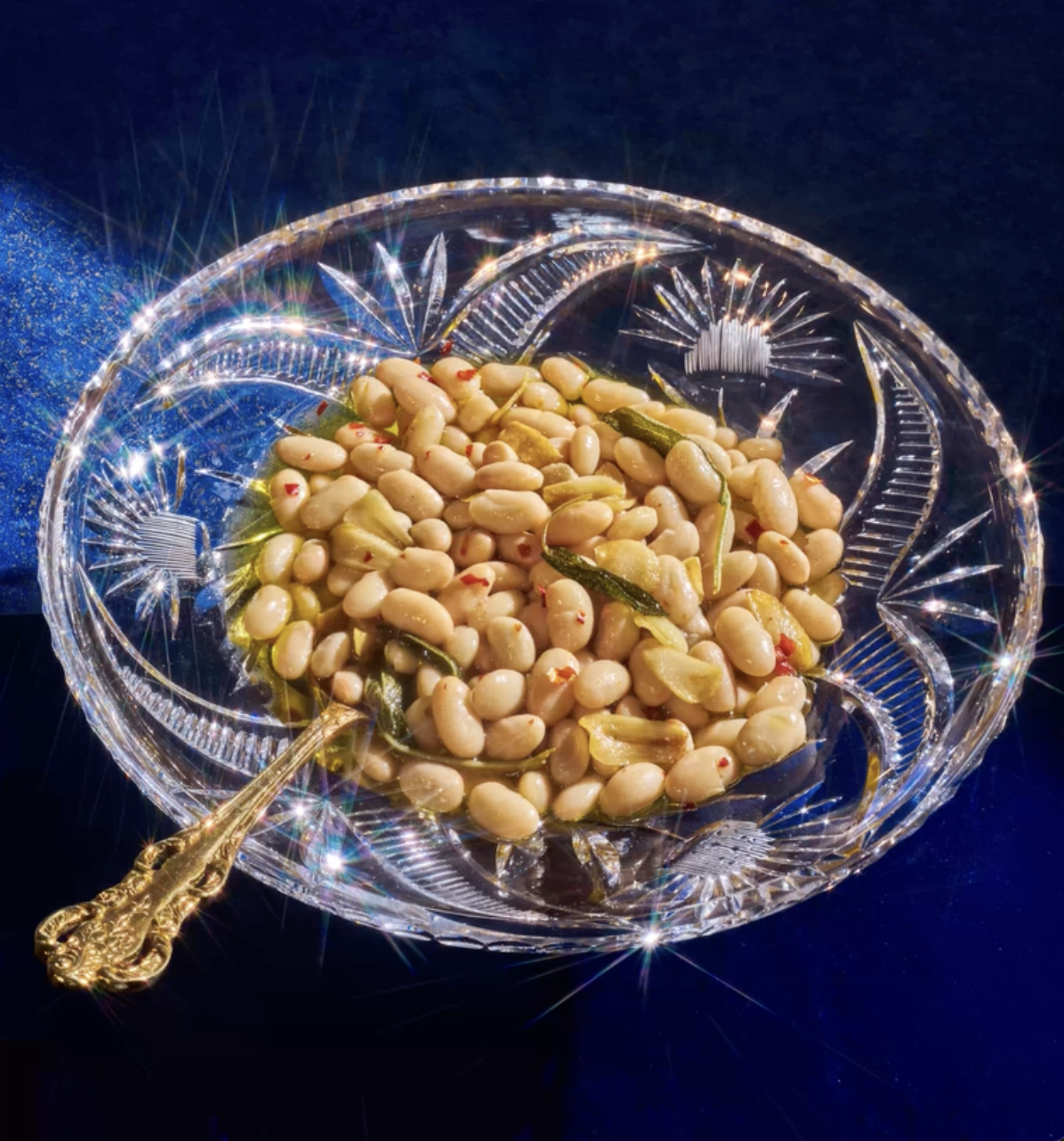 crystal dish of white beans with a fancy gold utensil